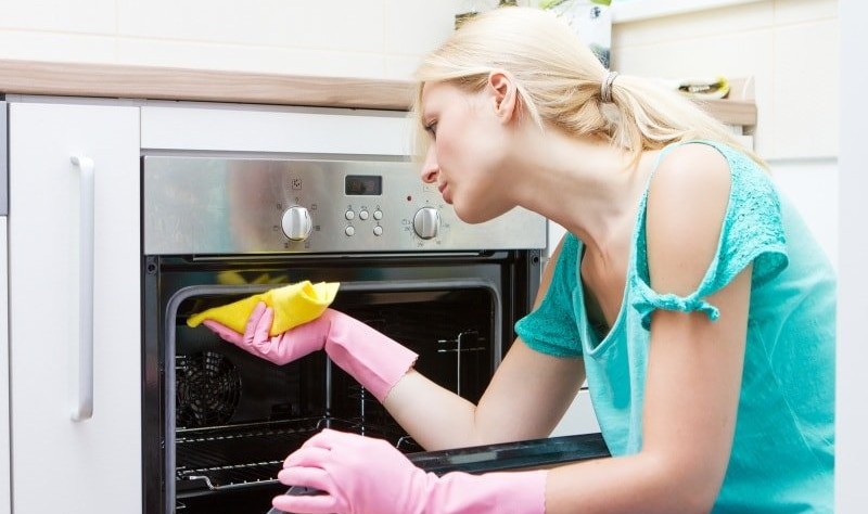 a woman is cleaning an oven