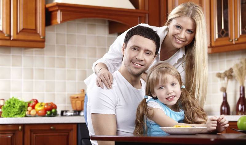 Woman, man and a kid is sitting inside a clean kitchen