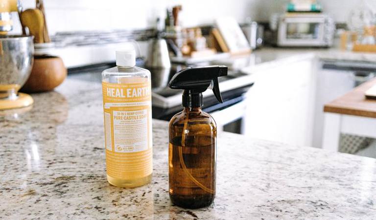 One yellow bottle and one brown bottle on marble cabinet inside a kitchen