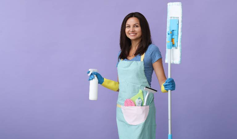 Woman in uniform holding a spray bottle and a mop in her hand.