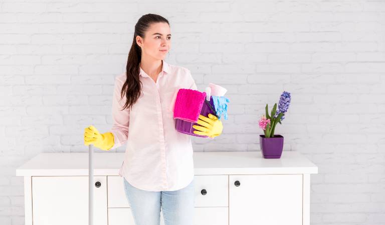 Woman in yellow glove holding a basket filled with tools products.