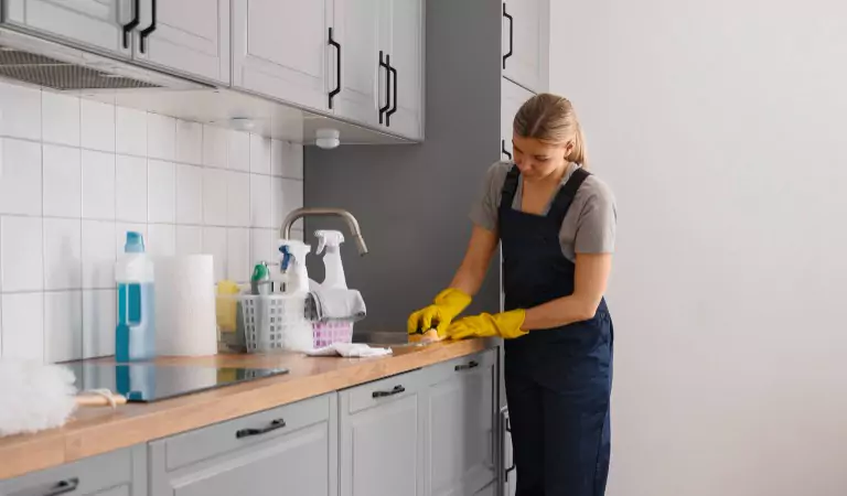 young woman cleaning the sink area inside of a kitchen
