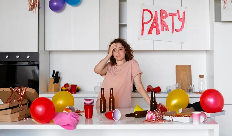 A tensed woman is standing in a dirty place after party.