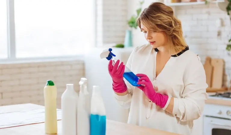 Lady in white dress and pink gloves checking something on a bottle.