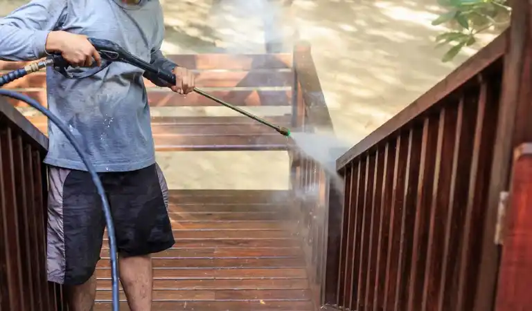 Man in shirt and half pant cleaning stairs using pressure washing