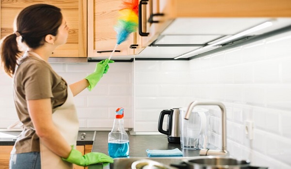 side-view-woman-cleaning-kitchen-with-duster.