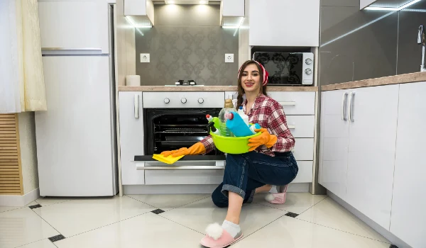 Woman with rubber gloves and disinfectant washes the floor in the kitchen
