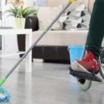 Woman in wheelchair washes the floor with mop indoor cleaning by people with disabilities