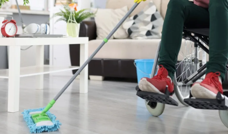 Woman in wheelchair washes the floor with mop indoor cleaning by people with disabilities