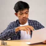 A young man is writing and organize his money