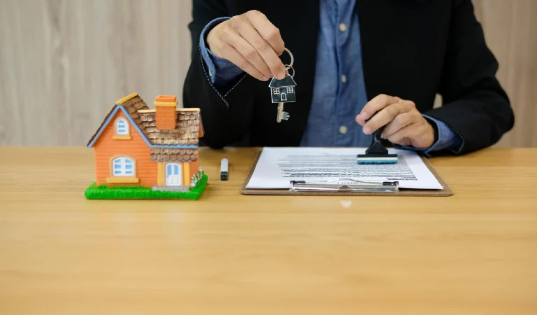 Midsection of businessman holding house key by papers on office desk
