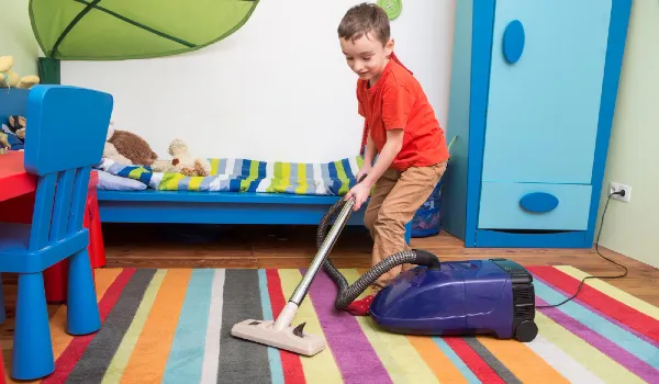 Cute boy cleaning floor with hoover the boy is cleaning up his room